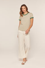 woman wearing a tan and green striped t-shirt with green ribbed neckline and white wide-leg pants