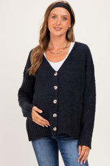 woman wearing a dark navy maternity cardigan with buttons, holding her baby bump, paired with a white top and jeans