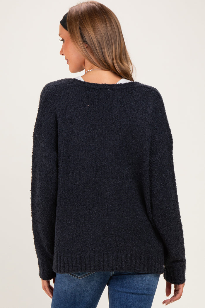 woman wearing a navy blue oversized maternity sweater, showing the back view, styled with a relaxed fit