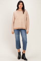 woman wearing a beige and white striped oversized sweater with blue cropped jeans and black ankle boots