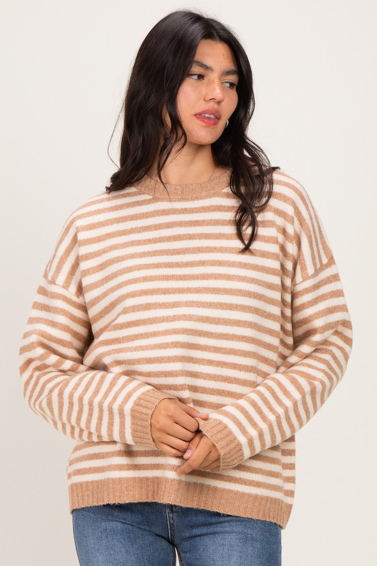 woman wearing a beige and white striped oversized sweater with long sleeves and a relaxed fit