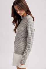 woman wearing a gray and white striped long sleeve top with a relaxed fit and paired with a white skirt