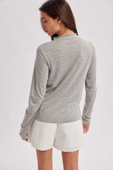 woman wearing a gray and white striped long sleeve top with back view and white shorts