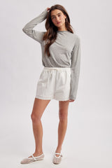 woman wearing a gray and white striped long sleeve top and white shorts with lace trim