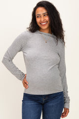woman wearing a gray and white striped maternity long sleeve top and smiling with a visible baby bump