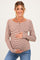 woman wearing a brown and white striped maternity top and holding her baby bump