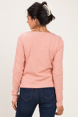 woman wearing a pink and white striped long sleeve top, showing the back view with dark jeans