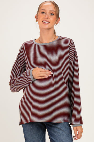 woman wearing a striped long sleeve maternity top and holding her baby bump