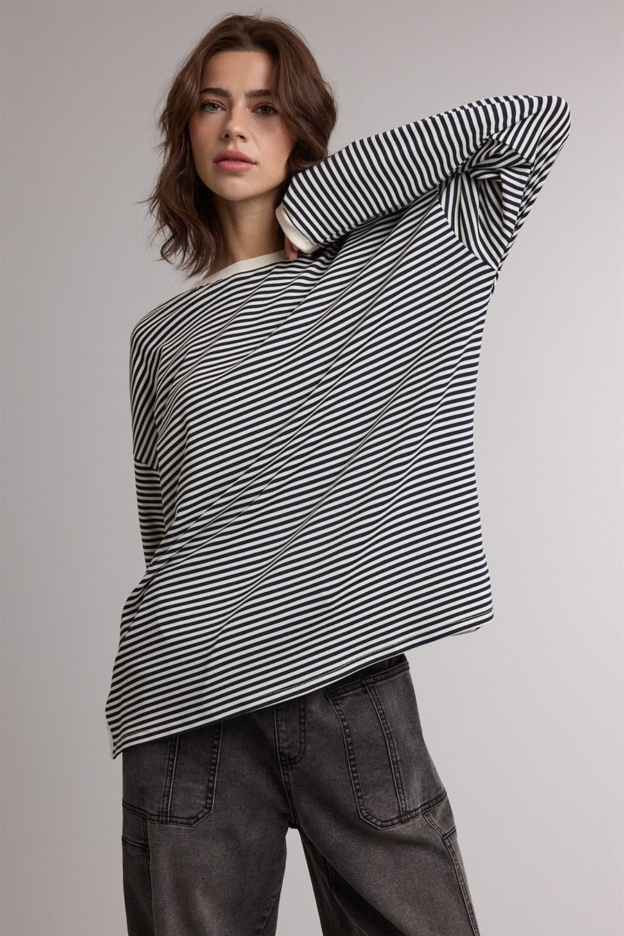 woman wearing a black and white striped oversized long sleeve top with a relaxed fit and dark gray trousers
