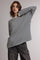 woman wearing a black and white striped oversized long sleeve top with a relaxed fit and dark gray trousers