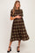 woman wearing a brown and green plaid maternity dress and holding her baby bump