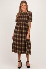 woman wearing a brown and green checkered maternity dress with short puff sleeves and a loose fit, displaying a baby bump