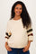 woman wearing a cream maternity sweater with striped sleeves and a visible baby bump, smiling at the camera