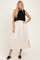 woman wearing a black knitted crop top over a cream maxi dress with side slits and black slide sandals