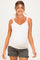 woman wearing a white maternity tank top with lace trim and holding her baby bump, paired with gray shorts
