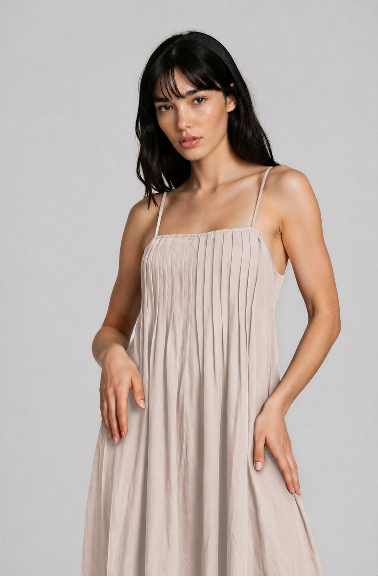 woman wearing a light beige pleated spaghetti strap dress
