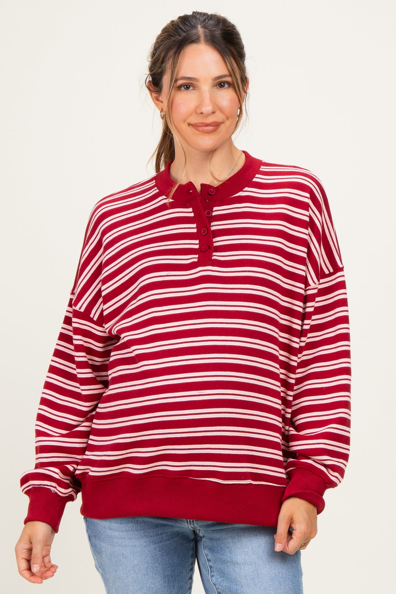 woman wearing a red and white striped maternity sweatshirt with a henley neckline and relaxed fit