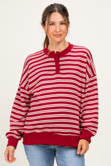 woman wearing a red and white striped maternity sweatshirt with a henley neckline and relaxed fit