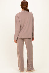 woman wearing a taupe long sleeve pajama set with matching pants and white trim details