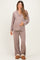 woman wearing a light taupe long sleeve maternity pajama set and holding her baby bump