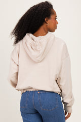 woman wearing a beige cropped hoodie with a ruched detail on the back and paired with high-waisted blue jeans