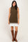woman wearing an olive green ribbed knit sleeveless dress with a white pleated skirt and knee-high brown boots