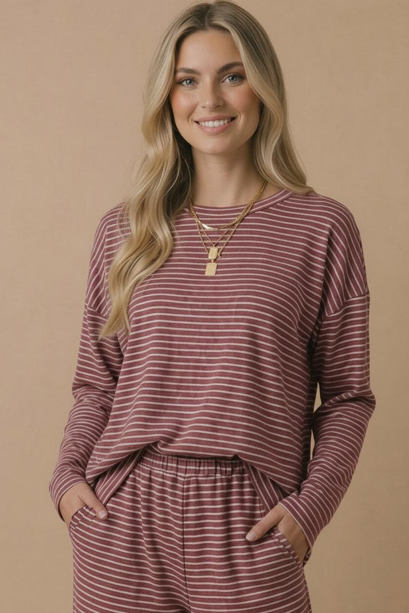 woman wearing a maroon and white striped long sleeve top with pockets and matching bottoms, smiling at the camera