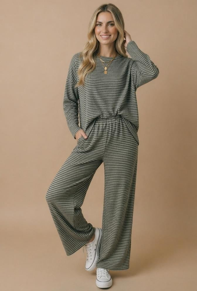 woman wearing a green and black striped long sleeve top and matching wide-leg pants with pockets and white sneakers