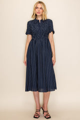 woman wearing a navy blue striped midi dress with a smocked waist and short sleeves