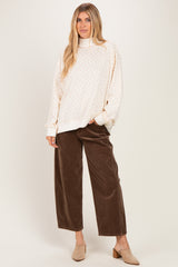 woman wearing a beige oversized sweatshirt with colorful dots and brown corduroy wide-leg pants