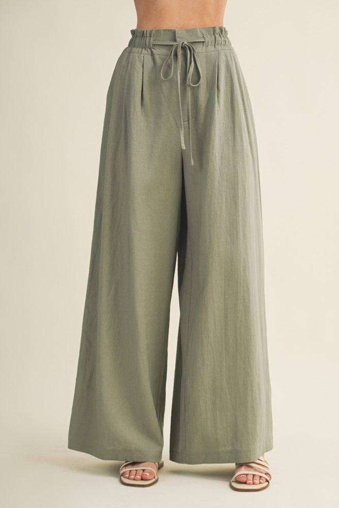 woman wearing light olive green wide-leg pants with an elastic waistband and drawstring detail