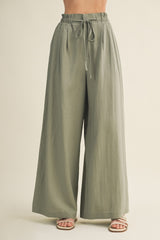 woman wearing light olive green wide-leg pants with an elastic waistband and drawstring detail