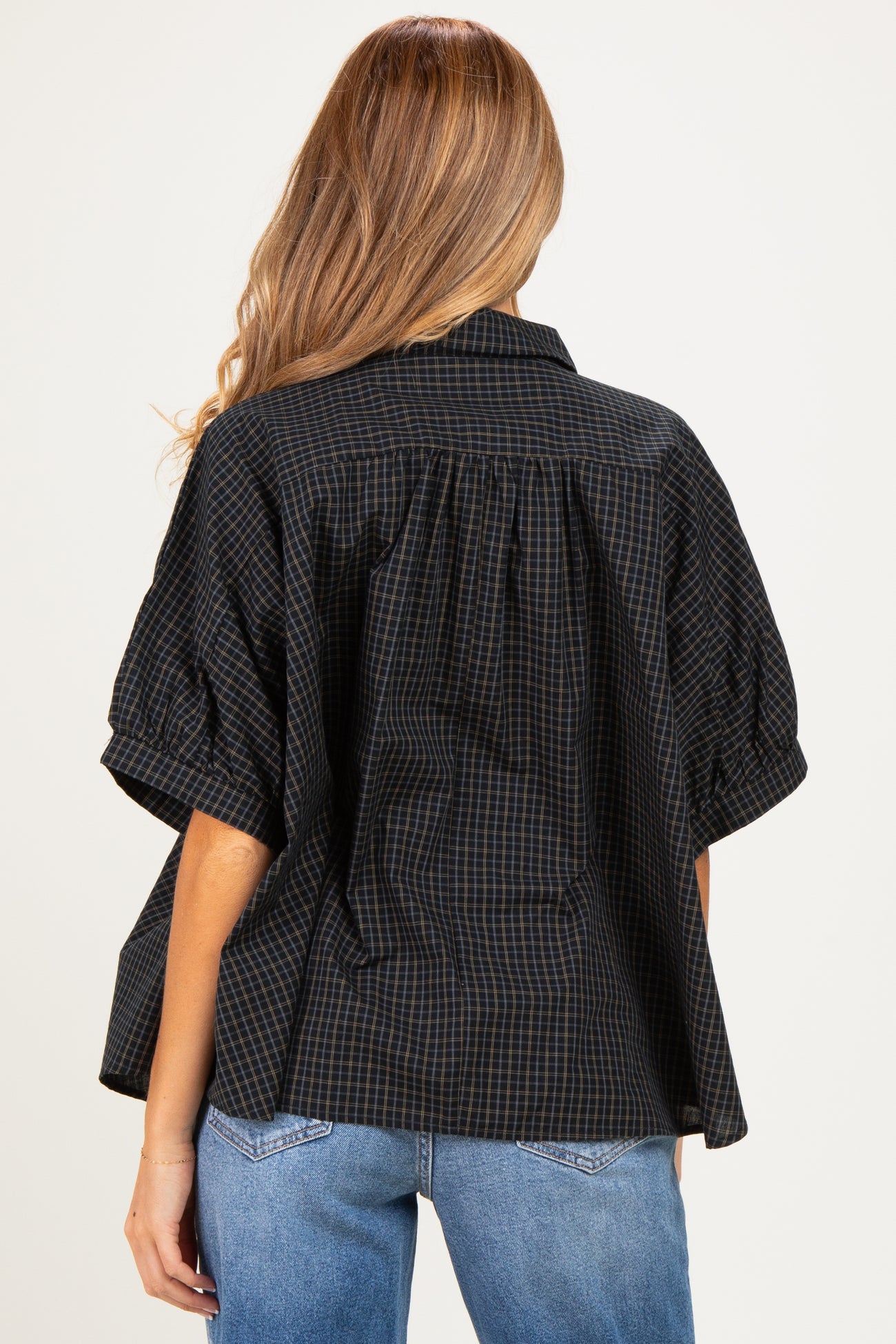 woman wearing a black and brown plaid maternity top with a loose fit and puffed sleeves, showing a baby bump from the back