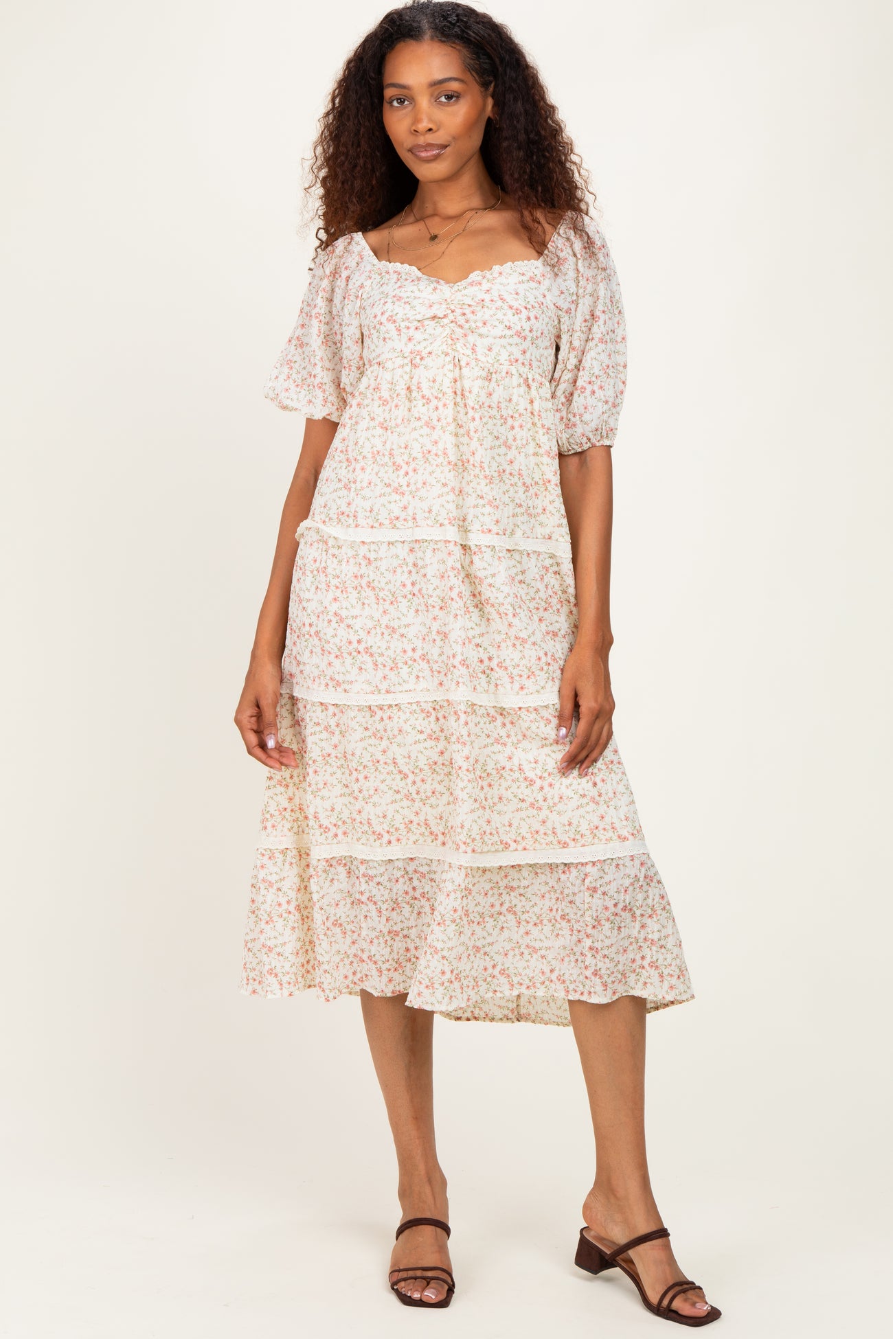 woman wearing a white floral tiered midi dress with puff sleeves and a ruffled hem