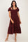 woman wearing a burgundy puff sleeve midi dress with white polka dots and a ruffled hem