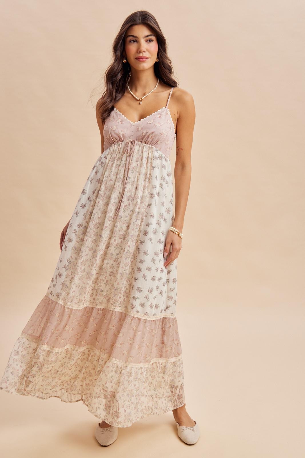 woman wearing a flowy floral maxi dress with spaghetti straps and tiered design in pastel colors