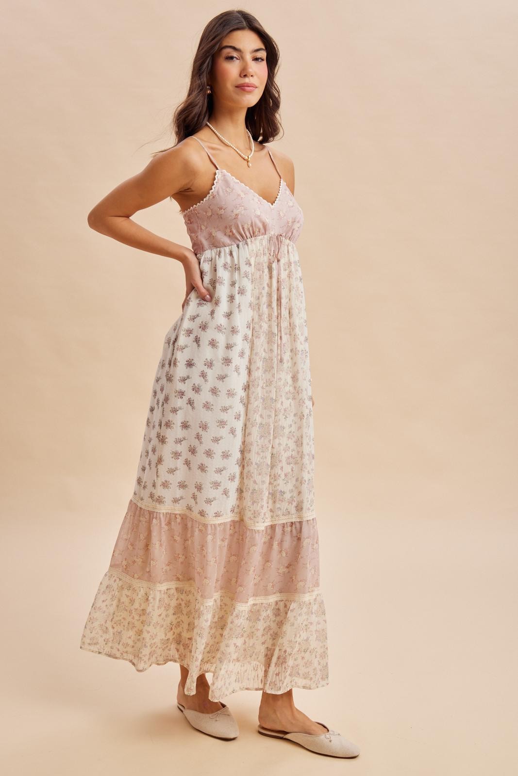 woman wearing a floral maxi dress with a pink bodice and tiered skirt, posing against a neutral background