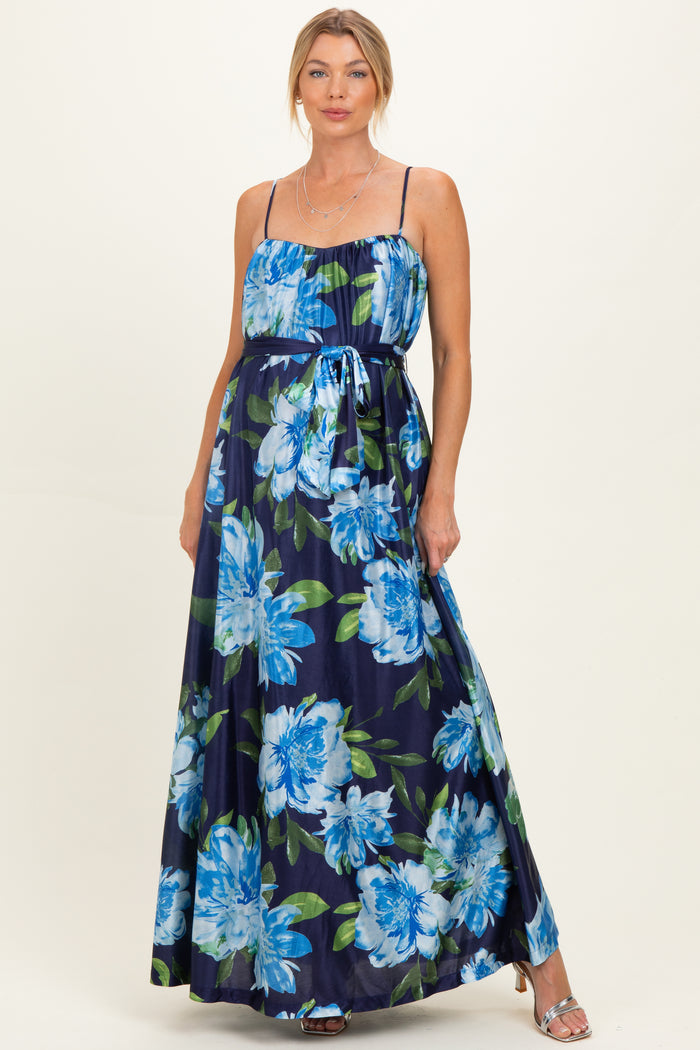 woman wearing a navy floral maternity maxi dress with a cinched waist and spaghetti straps, showcasing a baby bump