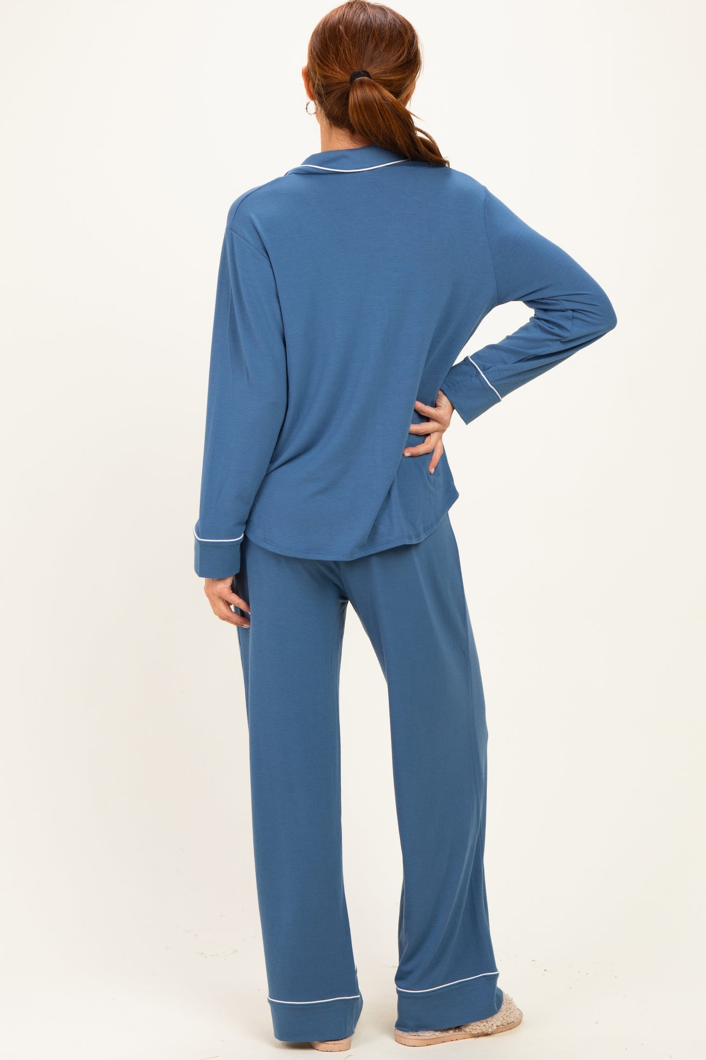 woman wearing a blue long sleeve pajama set with matching pants and white trim details, shown from the back