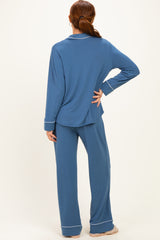 woman wearing a blue long sleeve pajama set with matching pants and white trim details, shown from the back