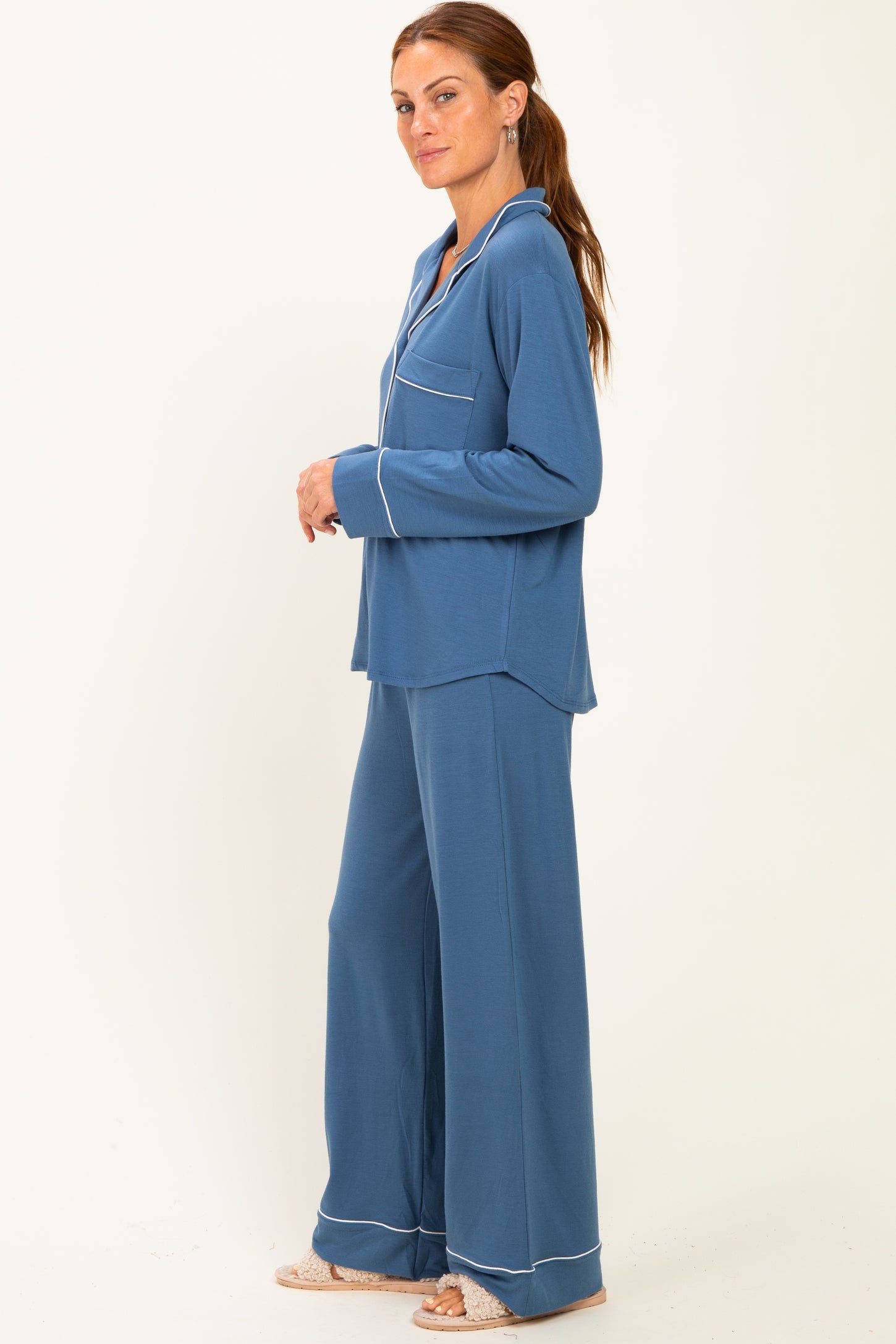 woman wearing a blue pajama set with a button-up top and wide-leg pants, featuring white trim details