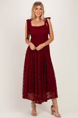 woman wearing a burgundy lace maxi dress with bow tie shoulder straps and a fitted bodice