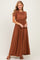 woman wearing a rust colored short sleeve maxi dress with an elastic waist and a relaxed fit