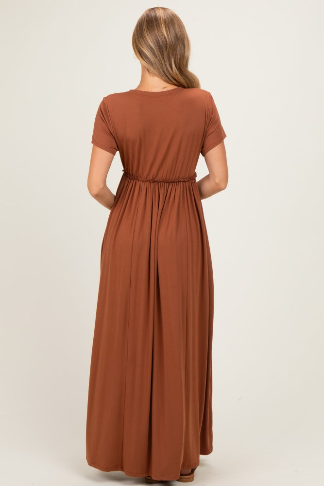 woman wearing a rust brown short sleeve maxi dress with a gathered waistband, viewed from the back