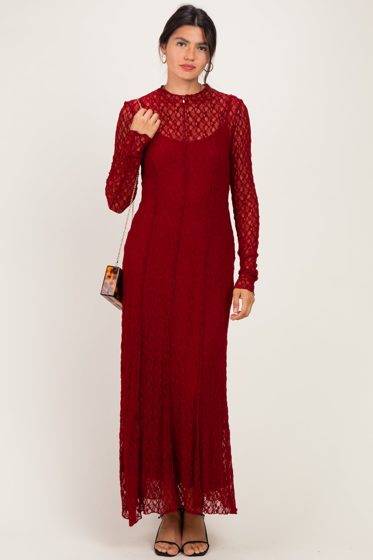 woman wearing a burgundy lace long sleeve maxi dress with a high neckline and a fitted silhouette