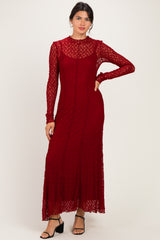 woman wearing a burgundy long sleeve lace maxi dress with a fitted silhouette and sheer details