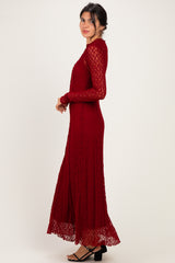 woman wearing a burgundy lace maxi dress with long sleeves and a flared skirt