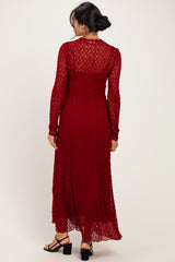 woman wearing a long sleeve burgundy lace maxi dress with a sheer back and flared hem, shown from the back