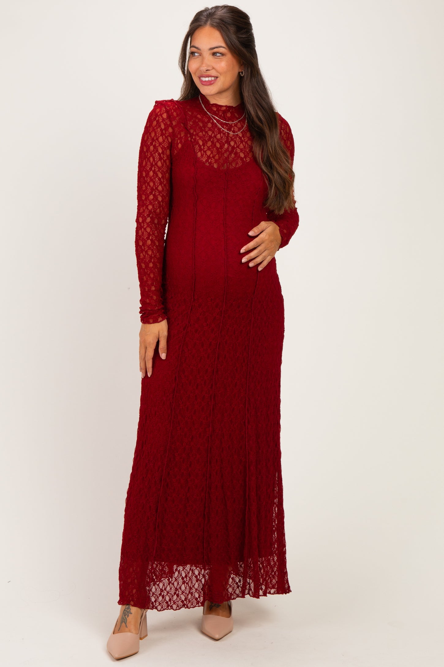 woman wearing a burgundy lace long sleeve maternity dress and showcasing her baby bump