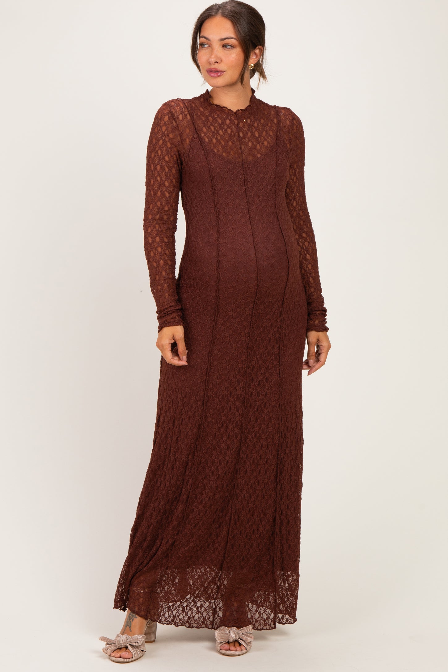 woman wearing a rust lace long sleeve maternity dress with a fitted silhouette and a flowing hem, showcasing her baby bump